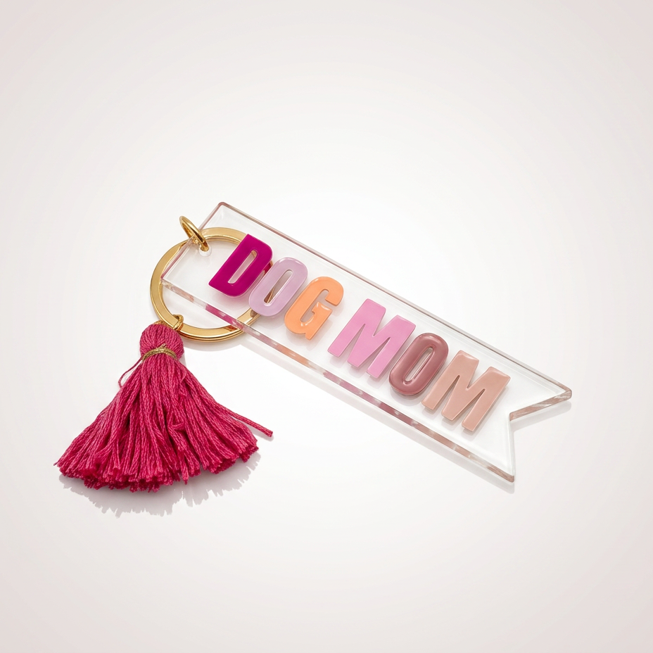 Keychain with 'DOG MOM' letters and pink tassel on a white background